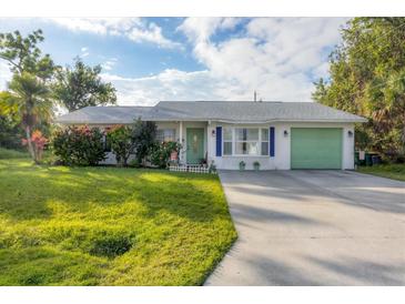 Cute single-story home with a green garage door and well-manicured lawn at 9261 Saint Catherine Ave, Englewood, FL 34224