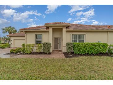Tan single-story home with a brown tile roof, neatly landscaped lawn, and a paved walkway to the front door at 13048 Creekside Ln, Port Charlotte, FL 33953