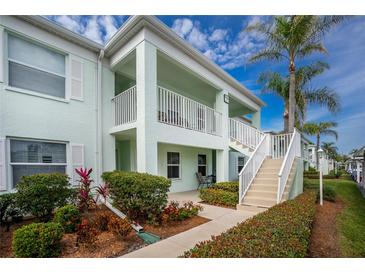 Light teal condo building with stairs, balcony, and landscaping at 5725 Greenwood Ave # 6204, North Port, FL 34287