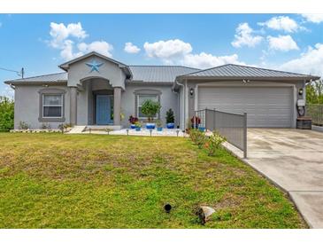 Gray house with metal roof, landscaping, and a two-car garage at 6153 Pennell St, Englewood, FL 34224