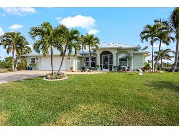 Light green house with palm trees, a large yard, and a two-car garage at 10322 Sunbury Dr, Port Charlotte, FL 33981