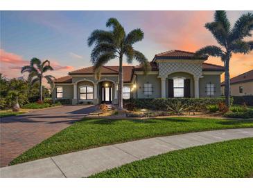Beautiful home featuring a landscaped front yard, palm trees, and a brick driveway at sunset at 10705 Tarflower Dr, Venice, FL 34293
