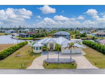 Aerial view of waterfront home with canal access, lush landscaping, and a large backyard at 15228 Chinook Way, Port Charlotte, FL 33981