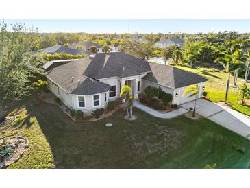 Single-story home with a large yard and a two-car garage, nicely landscaped at 13575 Chenille Dr, Port Charlotte, FL 33981