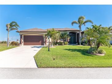 Single-story home with attached garage, lush landscaping, and palm trees at 214 W Pine Valley Ln, Rotonda West, FL 33947