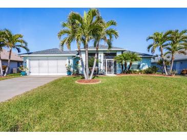 Charming home featuring a manicured lawn and complemented by swaying palm trees at 429 Rotonda Cir, Rotonda West, FL 33947