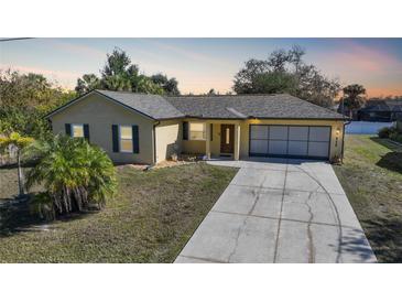 One-story home with a light yellow exterior, a driveway, and landscaping at 6176 Catalan St, Englewood, FL 34224