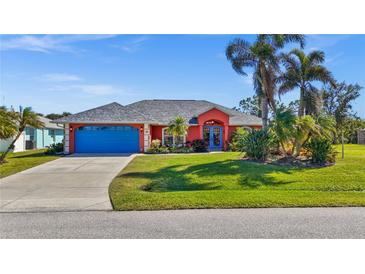 Bright coral house with blue garage door, lush landscaping, and palm trees at 62 Marker Rd, Rotonda West, FL 33947