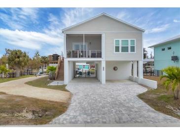 Two-story home with light beige siding, screened porch and paved driveway at 10451 Sherman St, Englewood, FL 34224