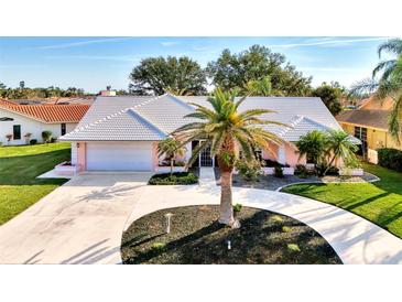 Beautiful single-story home with circular driveway, tropical landscaping, and an attached two-car garage at 1443 Quail Lake Dr, Venice, FL 34293