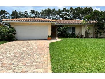 Brick ranch home with tile roof, large yard, and a paved driveway at 1755 Georgia Ne Ave, St Petersburg, FL 33703