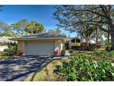 Charming single-story home featuring a two-car garage and a beautifully landscaped front yard with mature trees and flowering plants at 232 Southampton Ln # 259, Venice, FL 34293