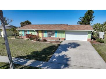 Charming single-story home featuring a well-manicured lawn, light green paint, and a spacious two-car garage at 6543 Coliseum Blvd, Port Charlotte, FL 33981