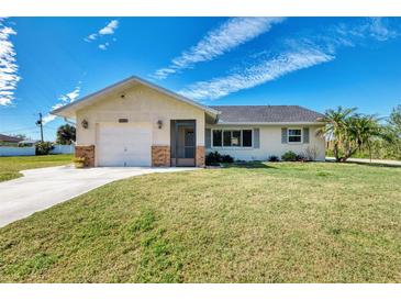 Single-story home with a white exterior, attached garage, and well-maintained lawn at 7179 Lighthouse St, Englewood, FL 34224