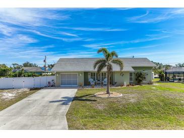 Cute Florida home with a palm tree, white fence, and spacious driveway at 7586 Sea Mist Dr, Port Charlotte, FL 33981