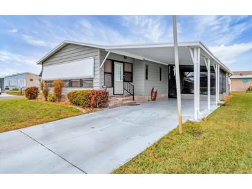 Gray mobile home with carport, landscaping, and paved driveway at 844 Seabrooke Ct, Englewood, FL 34223