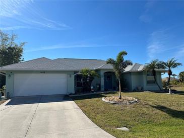 Light teal house with white garage and palm trees at 9458 Melody Circle, Port Charlotte, FL 33981