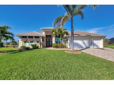 Charming single-story home featuring well-manicured lawn, mature palm trees and a spacious three car garage at 9676 Singer Cir, Port Charlotte, FL 33981