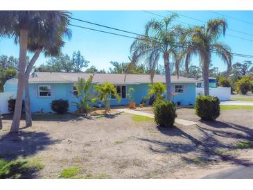 Charming single story home features mature landscaping with palm trees and a light blue exterior at 1005 E 2Nd St, Englewood, FL 34223