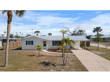Charming single-story home featuring a metal roof, a covered carport, and a well-maintained front yard with mature palm trees at 1455 New Point Comfort Rd, Englewood, FL 34223