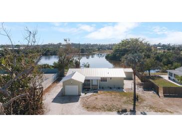 Charming single-story home with a metal roof, a one-car garage, and a waterfront view at 1493 New Point Comfort Rd, Englewood, FL 34223