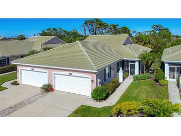 Inviting home featuring a two-car garage, well-kept lawn, and beautifully maintained landscaping at 1577 Monarch Dr # 1577, Venice, FL 34293