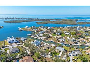 An aerial view of a coastal community showcases homes along canals leading to the open ocean at 405 Pelican Bnd, Placida, FL 33946