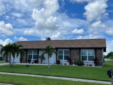 Charming single-story home with stone accents, well-manicured lawn, and beautiful landscaping at 6383 Coniston St, Port Charlotte, FL 33981