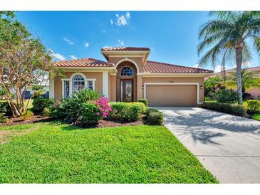 Charming home with a terracotta roof, lush landscaping, and well-manicured lawn on a sunny day at 13347 Golf Pointe Dr, Port Charlotte, FL 33953