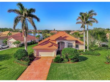 Beautiful single-Gathering home with a red tile roof, paver driveway, lush lawn, and tropical palm trees at 14405 Silver Lakes Cir, Port Charlotte, FL 33953