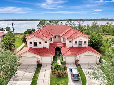 Stunning aerial view of a waterfront home with a red tile roof, lush landscaping, and a beautiful water view at 4754 Club Dr # 201, Port Charlotte, FL 33953