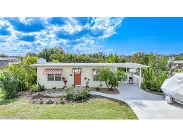 Cute bungalow with a landscaped lawn and striped awnings at 621 Tarpon Way, Punta Gorda, FL 33950