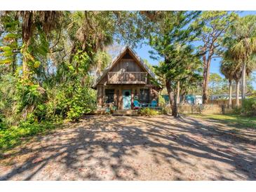 Charming A-frame home with a second-story balcony surrounded by lush, tropical foliage at 681 Olive St, Englewood, FL 34223