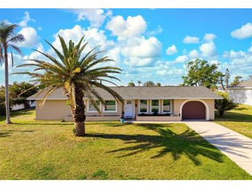 Charming single-story home with well-manicured lawn and mature palm trees at 84 Caddy Rd, Rotonda West, FL 33947