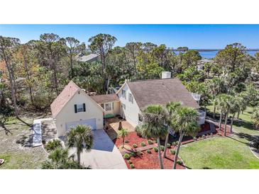 Charming two-story home with well-maintained landscaping, palm trees, and a view of the water at 955 Morrison Ave, Englewood, FL 34223