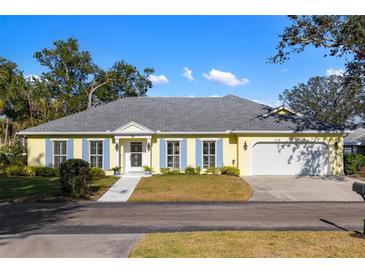 Charming one-story home with blue shutters and a well-maintained front lawn with blue skies overhead at 10 Bermuda Cir # 57, Englewood, FL 34223