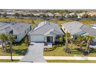 Charming single-story home with a gray-tiled roof, paver driveway and lush landscaping, providing excellent curb appeal at 18575 Midsummer Pl, Venice, FL 34293