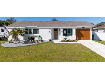 Charming single-story home with a well-manicured lawn, landscaping, and a cozy, inviting facade at 18970 Mcgrath Cir, Port Charlotte, FL 33948