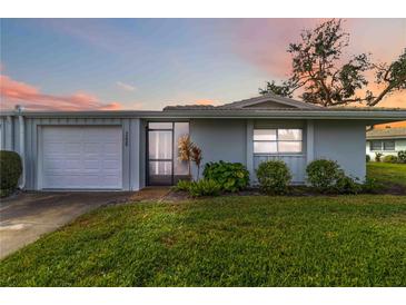 Well-maintained single-story home with an attached garage and lush green lawn at sunset at 3220 Southfield Ln # 810, Sarasota, FL 34239