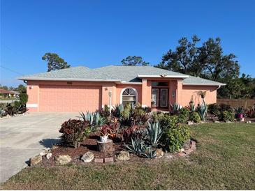 Charming coral home showcasing a beautiful front yard with lush, colorful landscaping and a gray roof at 501 Cobalt Rd, Englewood, FL 34223