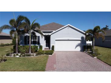 Single-story home with gray exterior, white garage door, and palm trees at 24692 Rio Villa Lakes Cir, Punta Gorda, FL 33950
