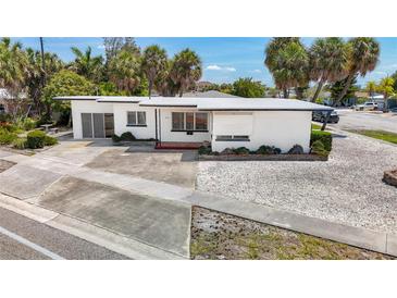 White single story home with a large front yard, driveway, and palm trees at 8701 Gulf Blvd, St Pete Beach, FL 33706