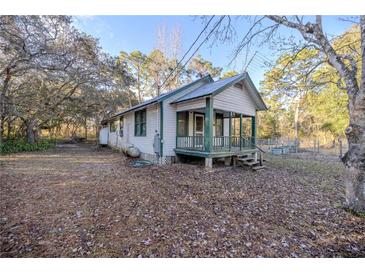 White house with green trim and porch, nestled on a wooded lot at 11317 Salina St, Brooksville, FL 34614