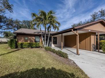 Tan house with brown roof, carport, and lush landscaping at 1700 Curry Trl # 35, Nokomis, FL 34275