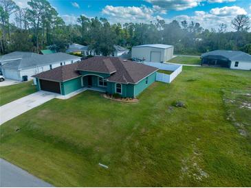 Aerial view of a teal house with brown roof, detached garage, and fenced backyard at 4154 Duluth Ter, North Port, FL 34286