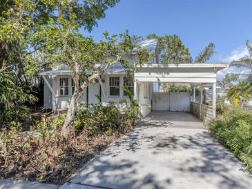 Charming two-story home with white paint, a carport, a concrete driveway, and lush landscaping at 112 Nippino W Trl, Nokomis, FL 34275