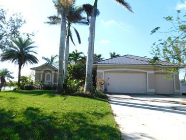 Inviting single-story home with a two car garage, lush lawn, and a tropical landscape at 24289 Toth Ln, Punta Gorda, FL 33955