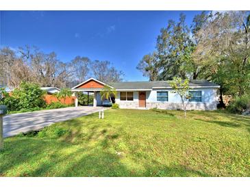 Charming one-story home featuring a carport, light blue exterior, and a well-maintained front yard at 1413 May St, Lutz, FL 33548