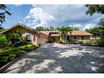 Charming home featuring an attached garage, lush landscaping, brick pathway, and a gravel driveway at 2521 Northway Dr, Venice, FL 34292