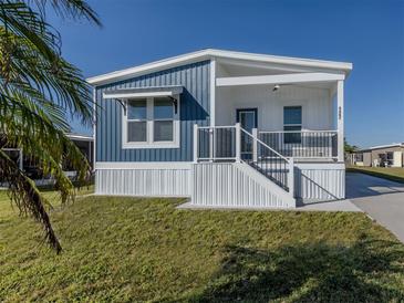 Single-wide home with blue and white siding, covered porch, and landscaped lawn at 127 Nautical Dr, North Port, FL 34287